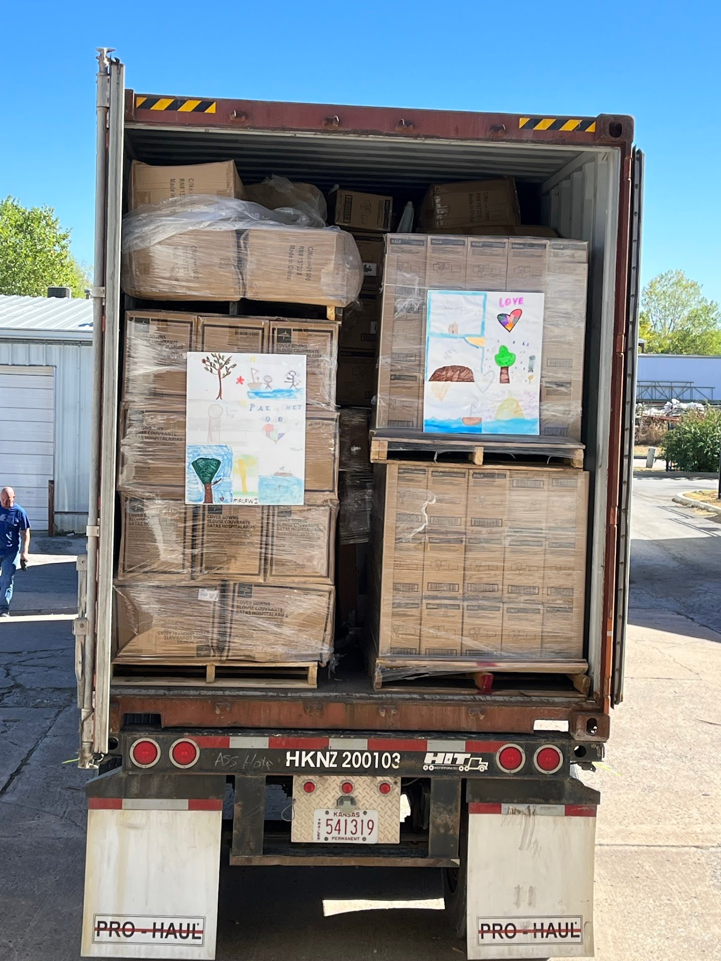 Shipping container fully loaded with pallets of donated medical supplies, decorated with handmade thank-you posters bound for Malawi